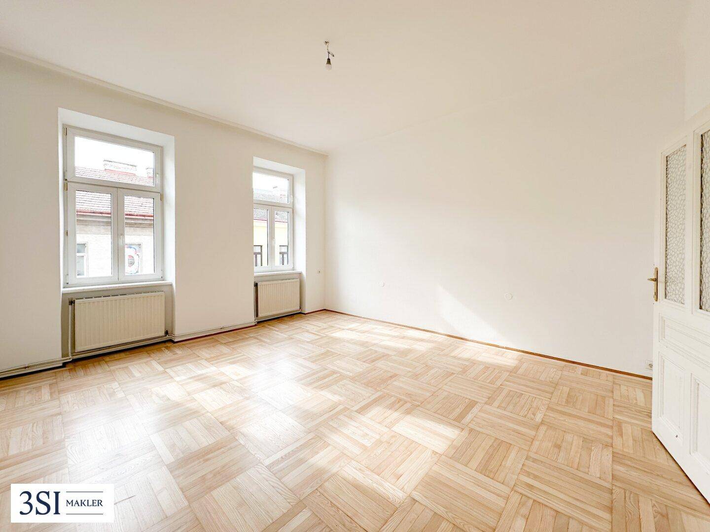 Geräumiges, helles Zimmer mit klassischem Parkettboden und hohen Decken, bereit zur individuellen Gestaltung.