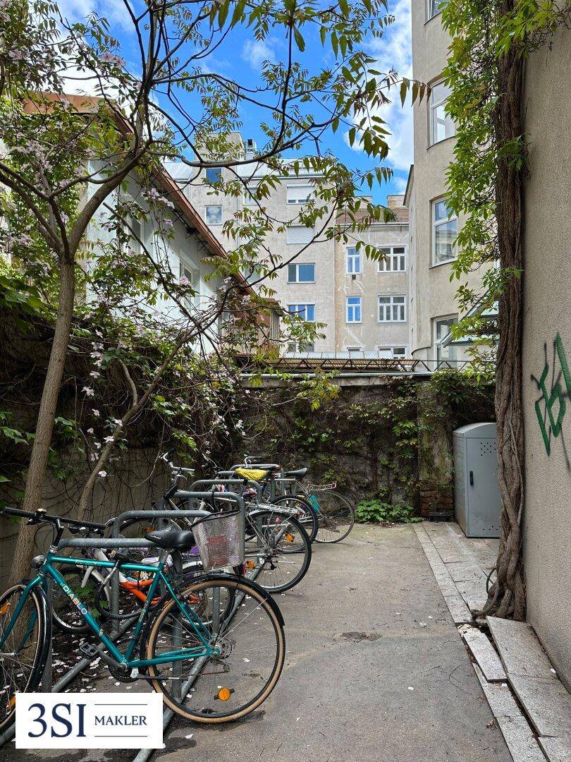 Fahrradabstellplatz im begrünten Innenhof mit Rankpflanzen und Bäumen.