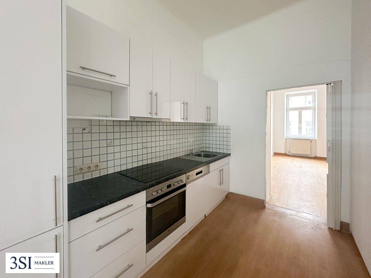 Funktionale Küche mit weißen Schränken, Fliesenrückwand und integrierten Geräten.