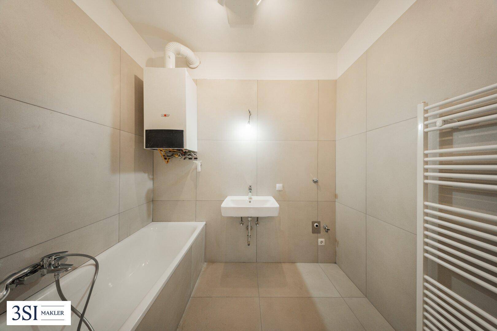 Badezimmer mit Badewanne, Waschbecken und Gastherme, ausgestattet mit hellen Wand- und Bodenfliesen.