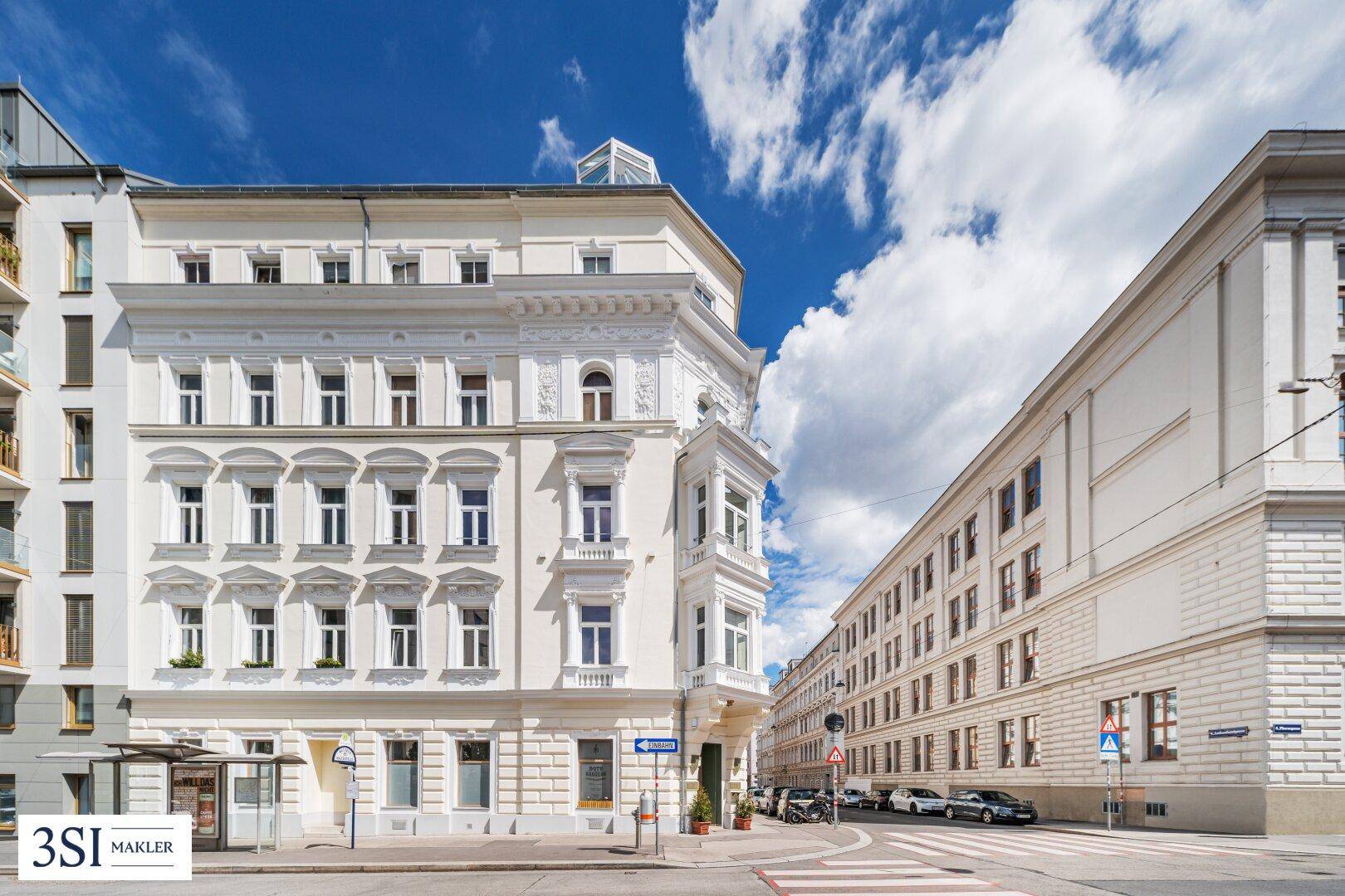Historisches Eckgebäude mit klassischer Architektur und reich verzierten Fassadendetails an einer belebten Straße.
