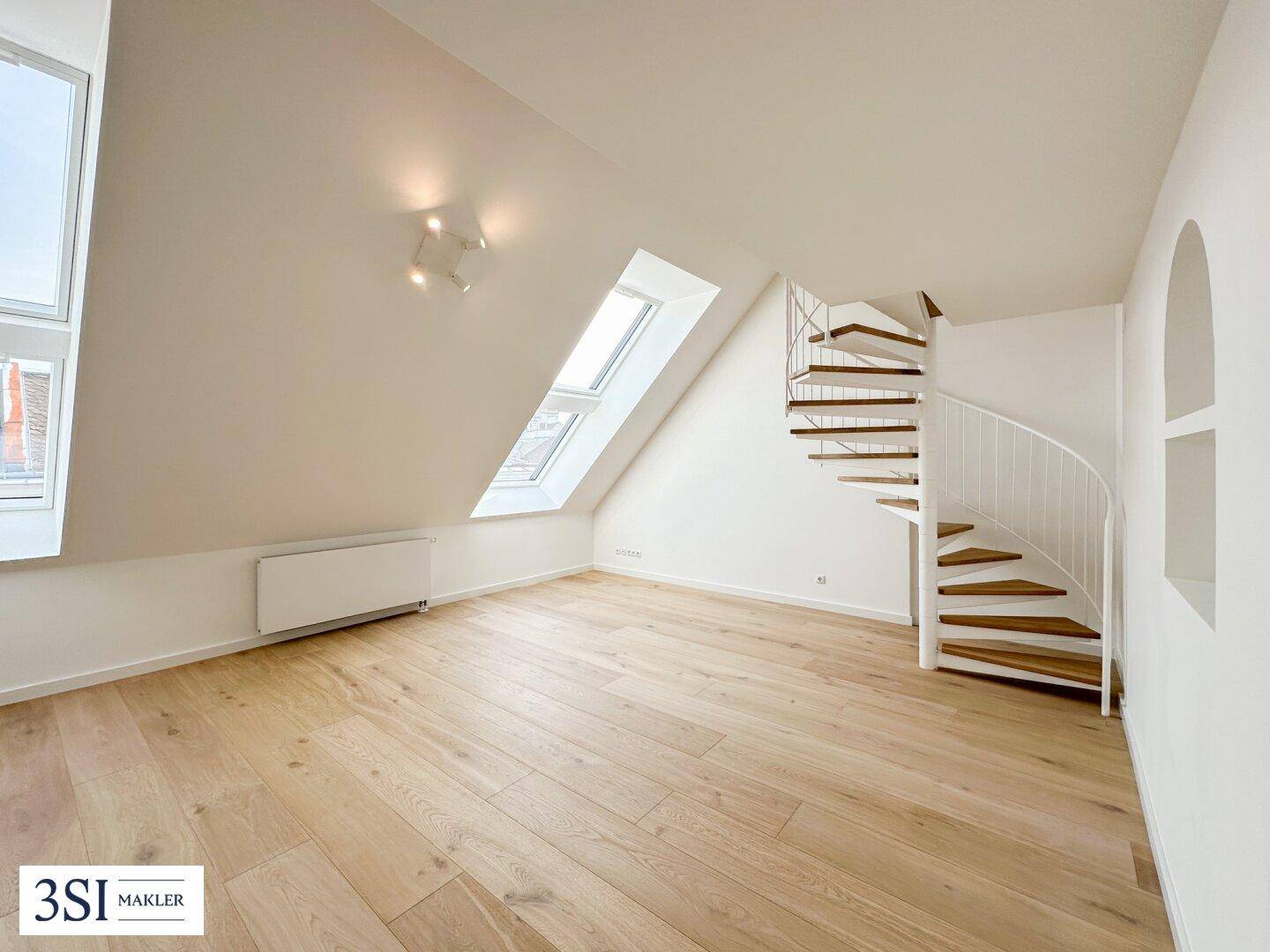 Heller Dachbodenraum mit schrägen Wänden, Dachfenstern und einer eleganten Wendeltreppe.