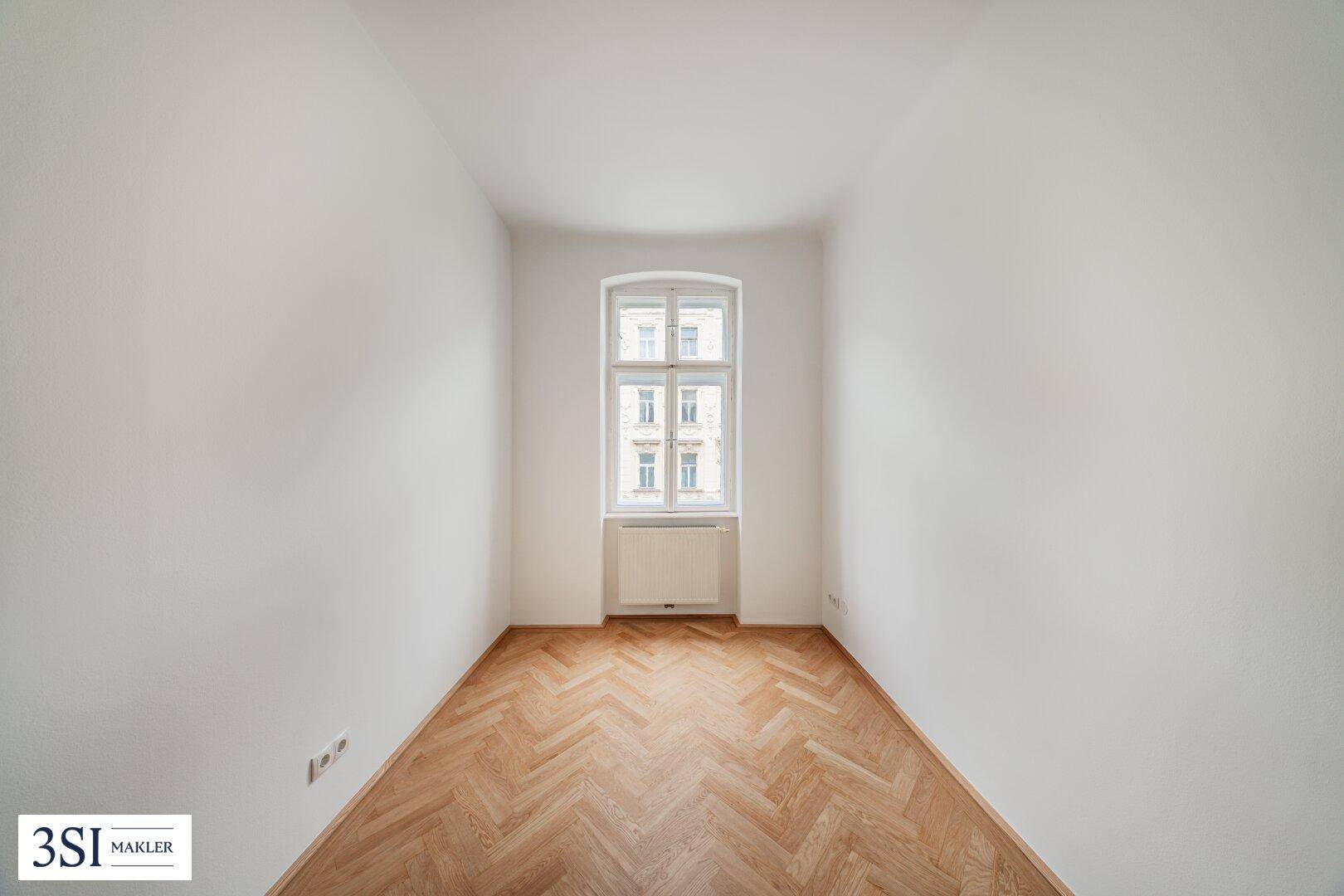 Kleineres, helles Zimmer mit einem Fenster und Fischgrätparkett, ideal als Büro oder Kinderzimmer.