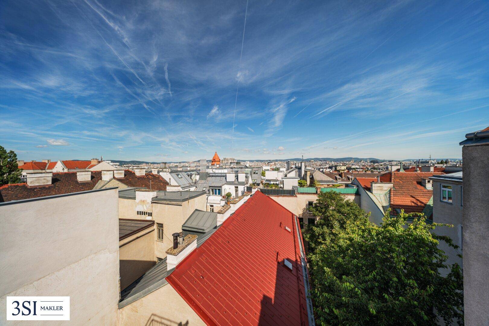 Weitläufiger Blick über die Dächer der Stadt unter einem klaren blauen Himmel.
