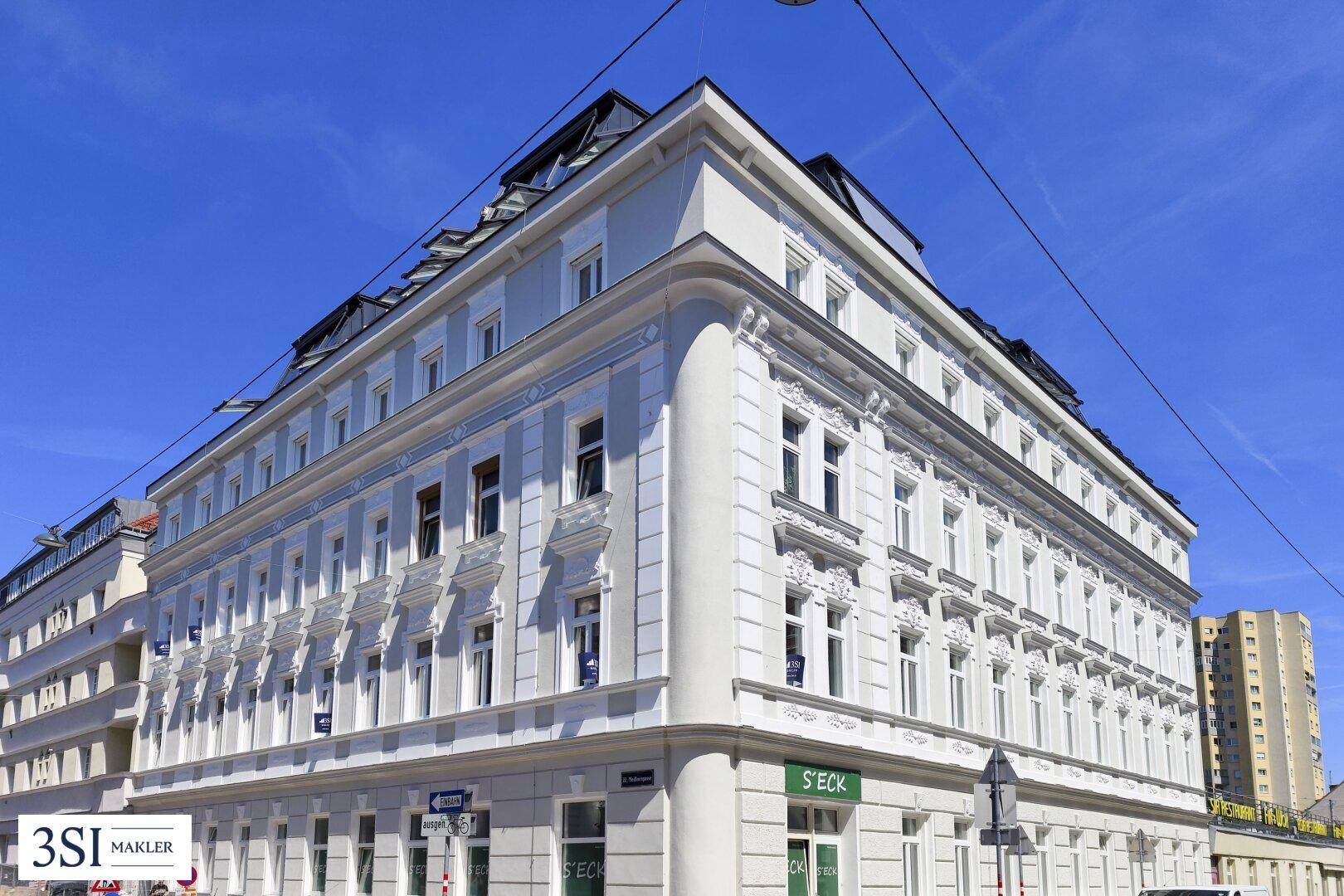 Elegantes Eckgebäude mit klassischer Architektur, vielen Fenstern und einem Mansarddach in der Stadt.