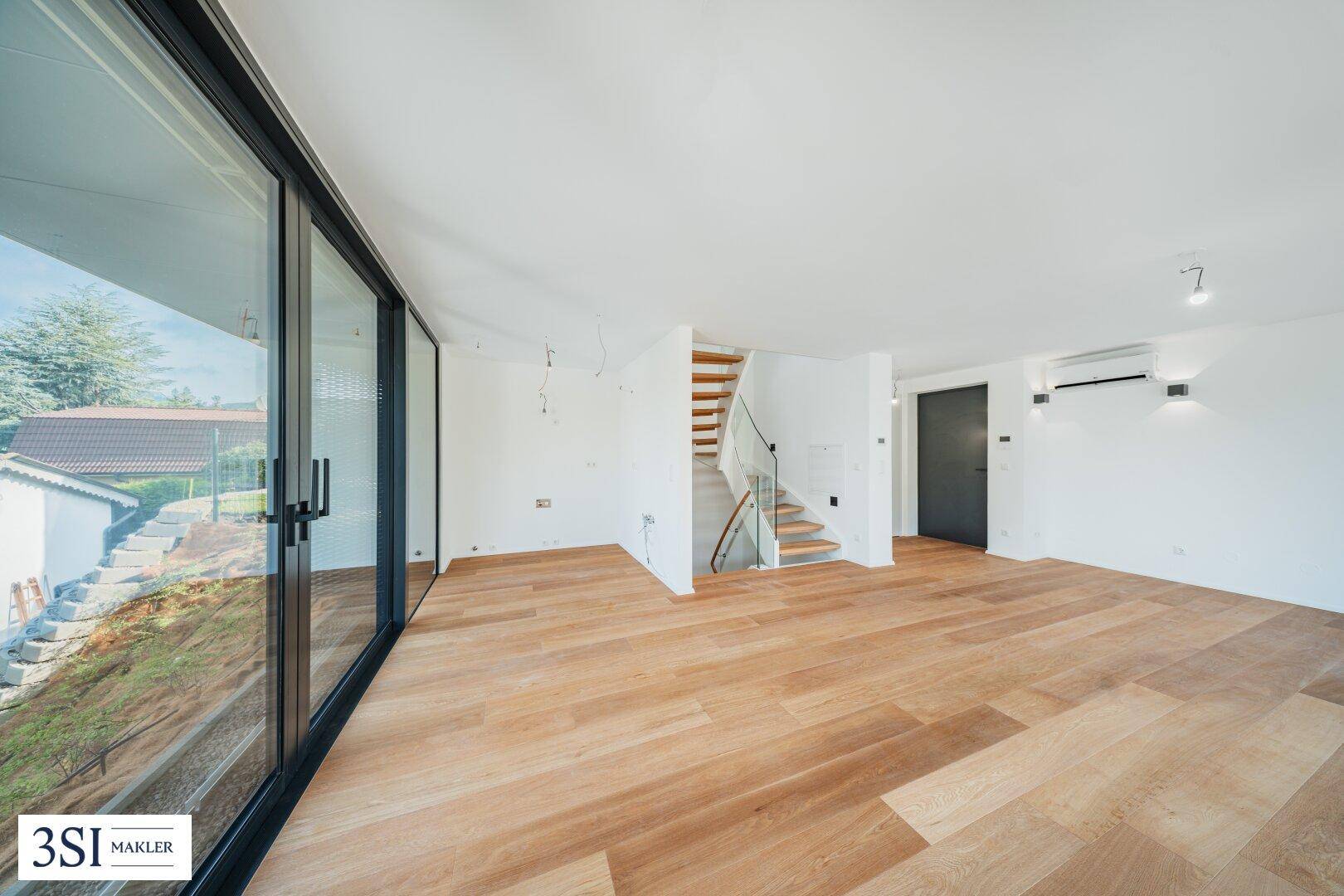 Heller Wohnbereich mit Holzboden, großen Schiebetüren und einer eleganten Holztreppe.