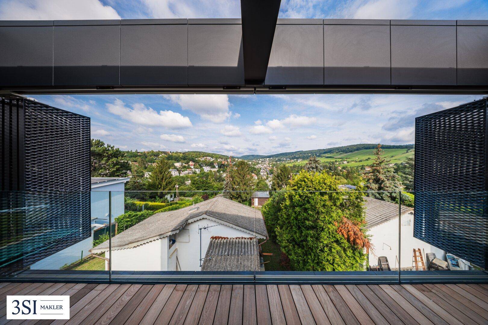 Weitblick über eine grüne Hügellandschaft von einem modernen Balkon mit Holzbelag.