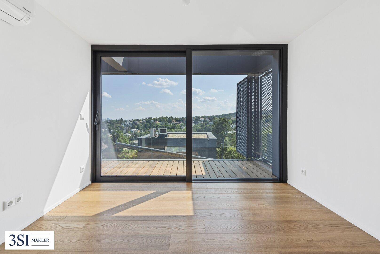 Helles Schlafzimmer mit Holzboden und großer Schiebetür, die Zugang zu einem Balkon bietet.