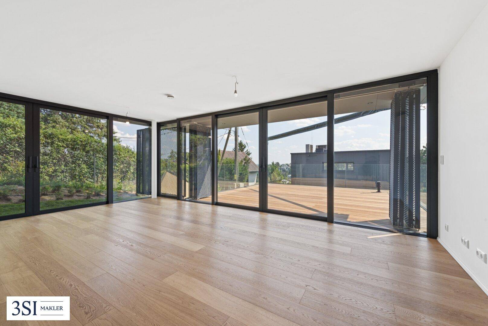 Heller, leerer Wohnraum mit Eichenparkett und raumhohen Fenstern, die auf eine Terrasse führen.