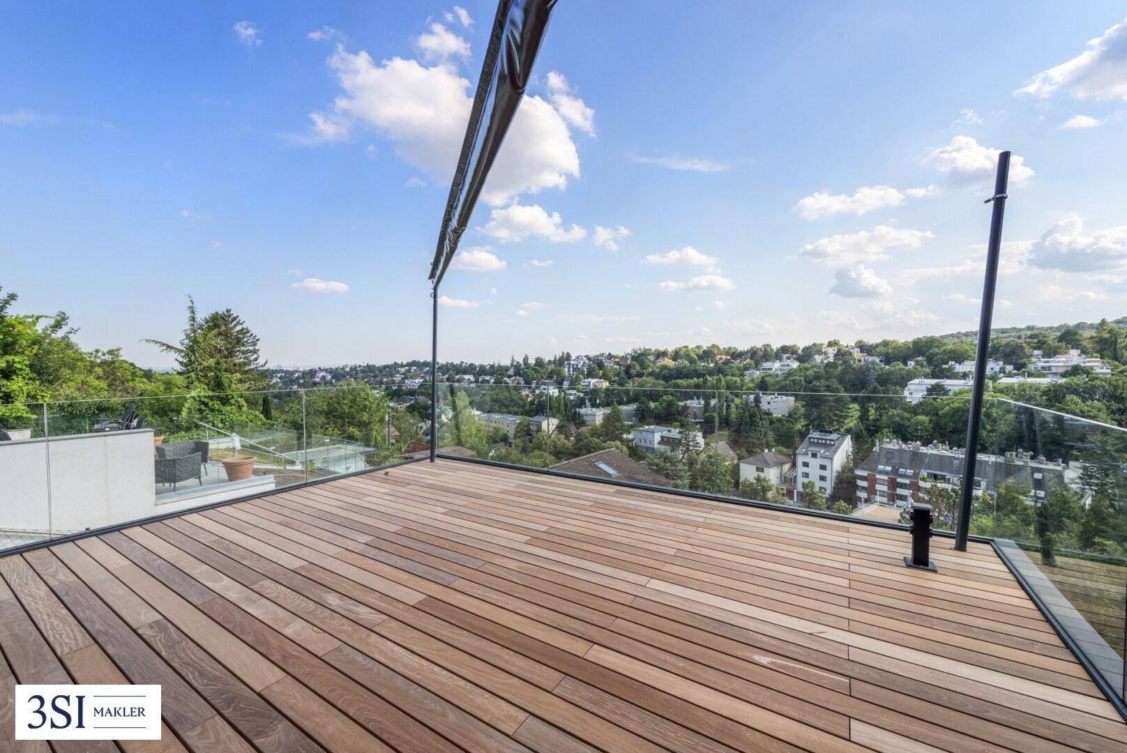 Weitläufige Holzterrasse mit Glasgeländer und beeindruckendem Panoramablick über die Stadt und Natur.
