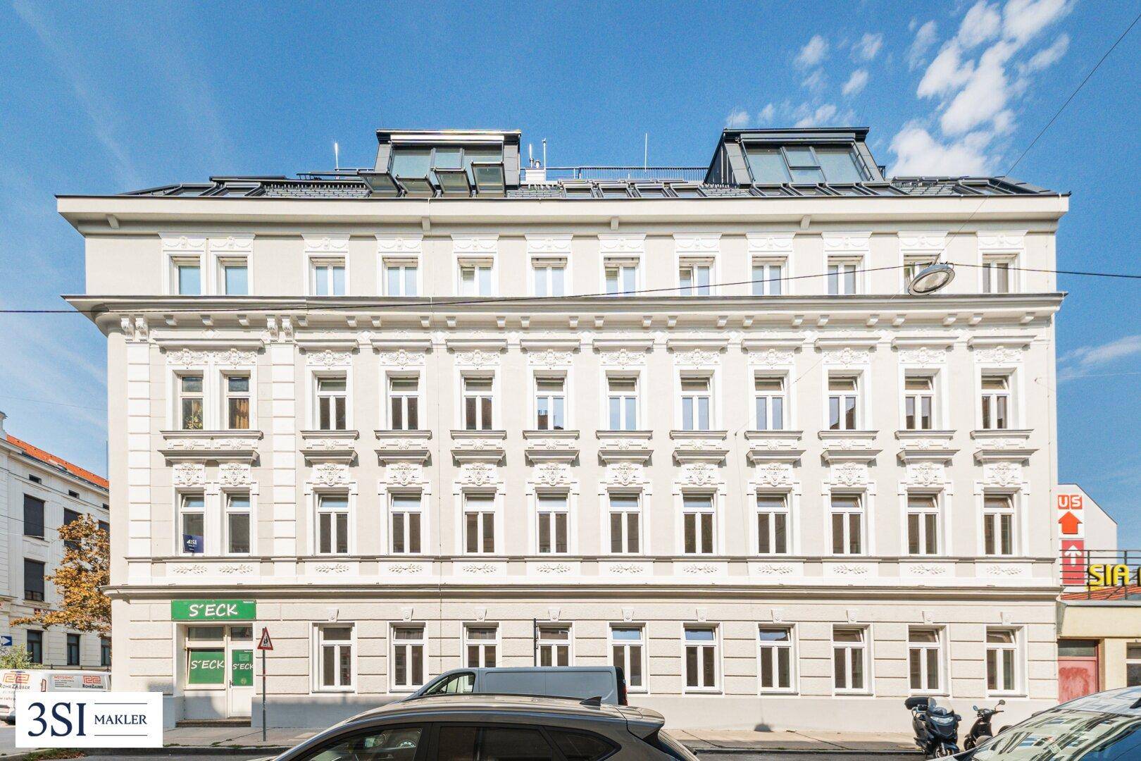 Klassisches Altbaugebäude mit reich verzierten Fassaden und Dachgauben unter blauem Himmel.