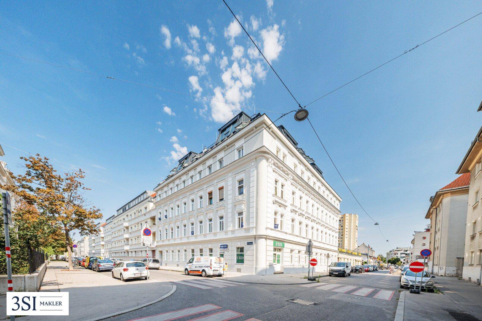 Historisches Eckgebäude in einer städtischen Umgebung mit viel Tageslicht und klarem Himmel.