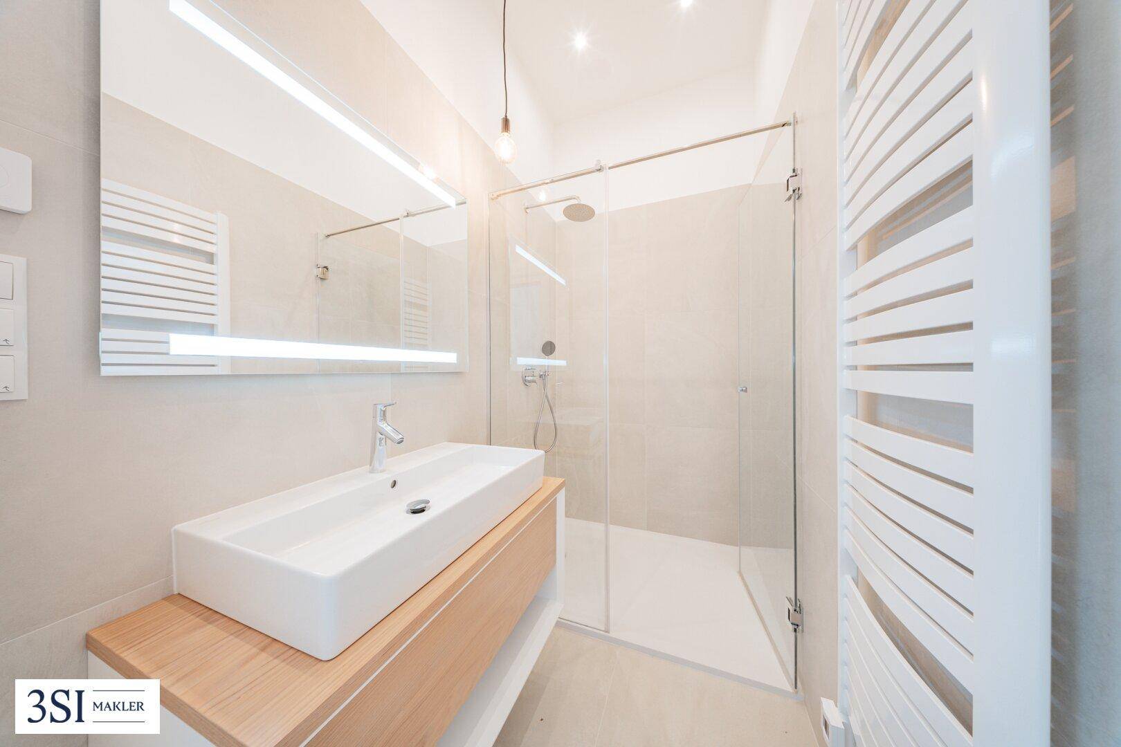 Modernes Badezimmer mit begehbarer Dusche, Einzelwaschbecken und beheiztem Handtuchhalter.