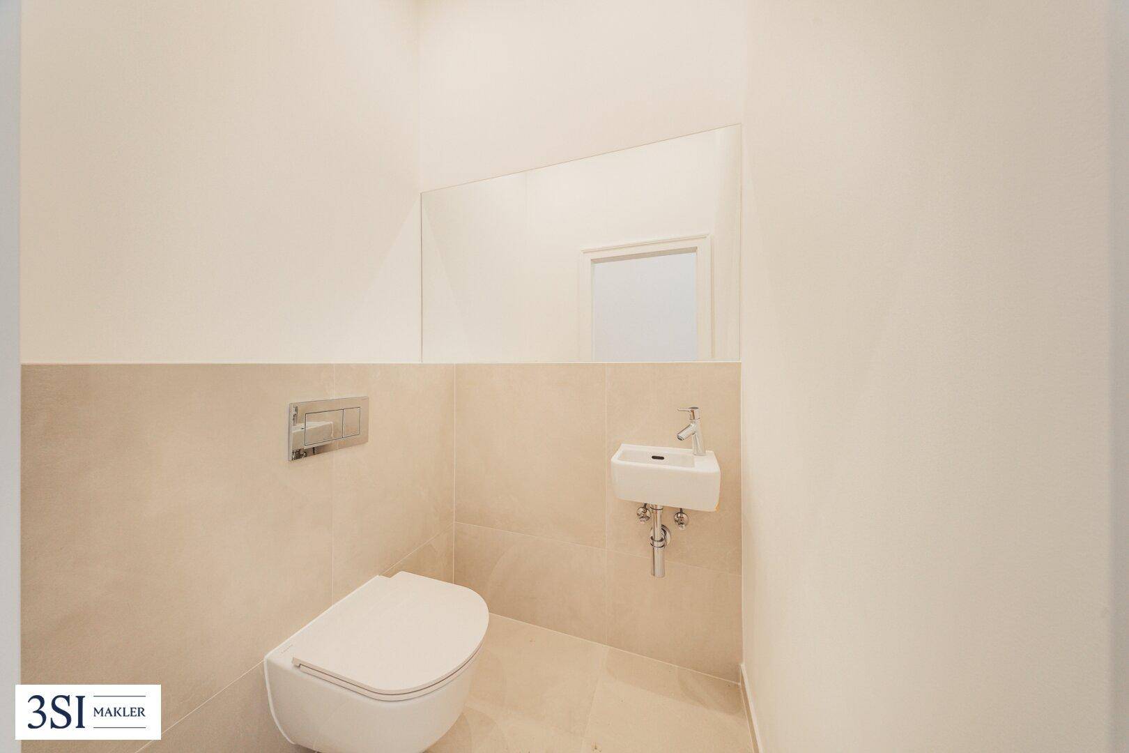 Modernes Gäste-WC mit wandhängender Toilette und kleinem Handwaschbecken.