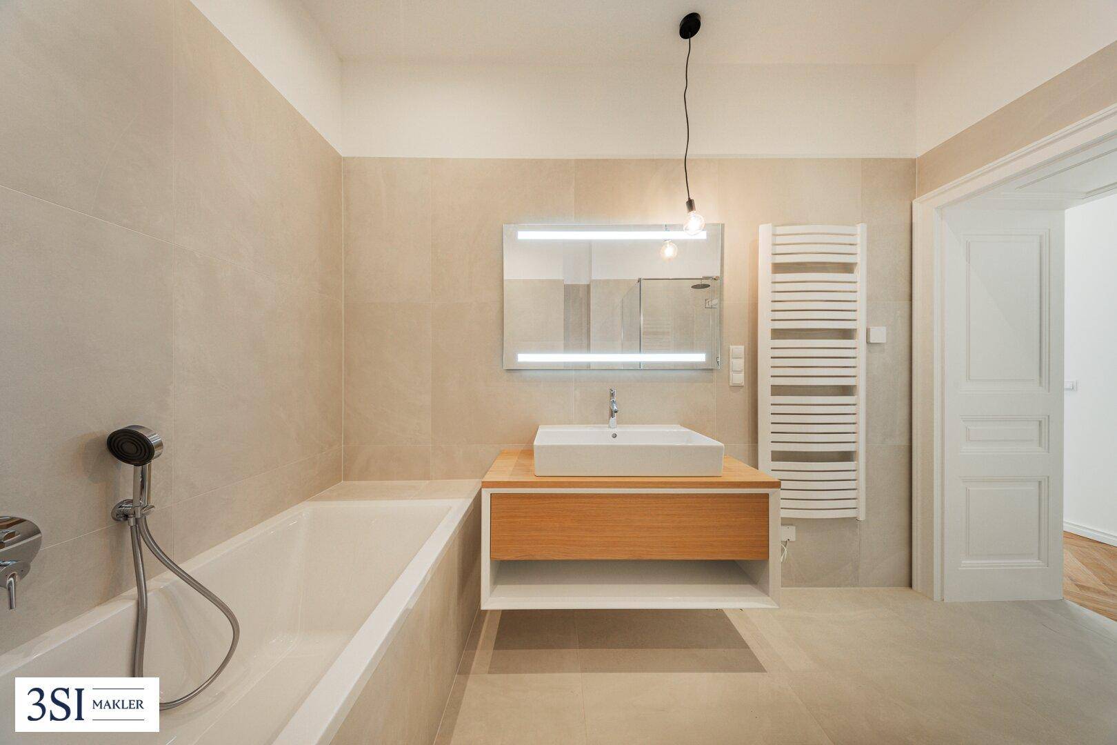 Helles Badezimmer mit Badewanne, modernem Waschtisch und beheiztem Handtuchhalter.