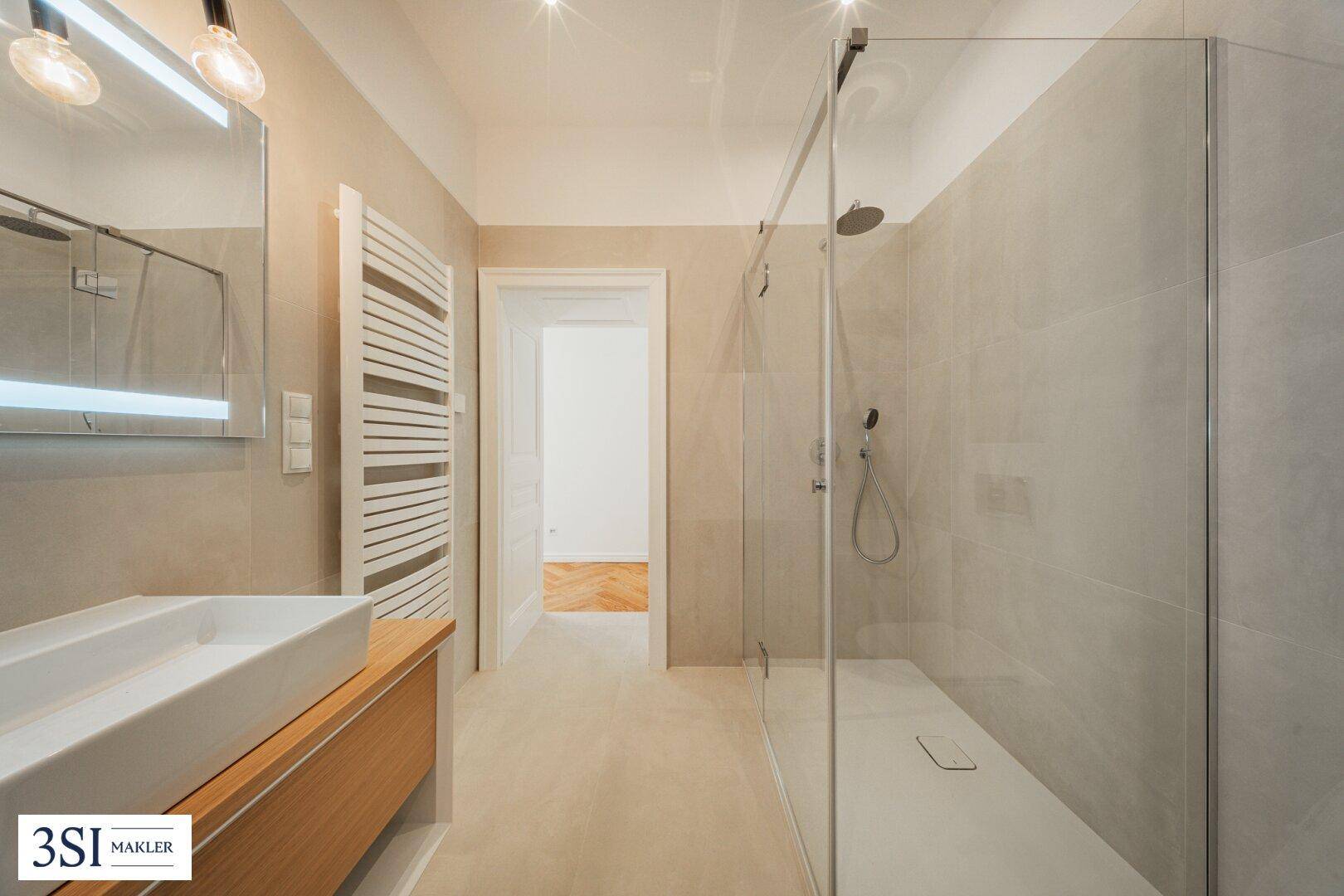 Elegantes Badezimmer mit großer begehbarer Dusche, modernem Waschtisch und Fliesenboden.