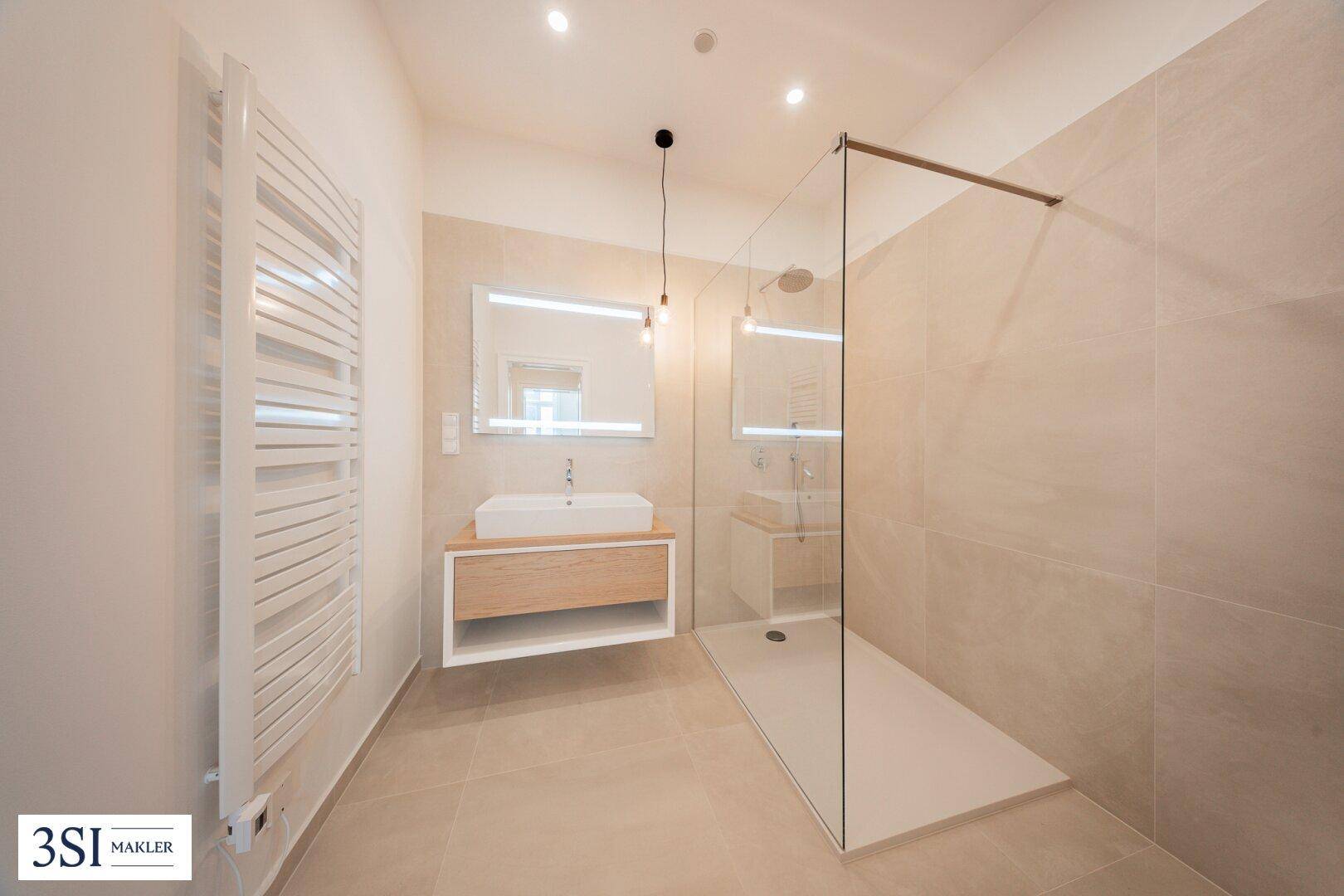 Modernes Badezimmer mit begehbarer Dusche, eleganten Fliesen und beheiztem Handtuchhalter.