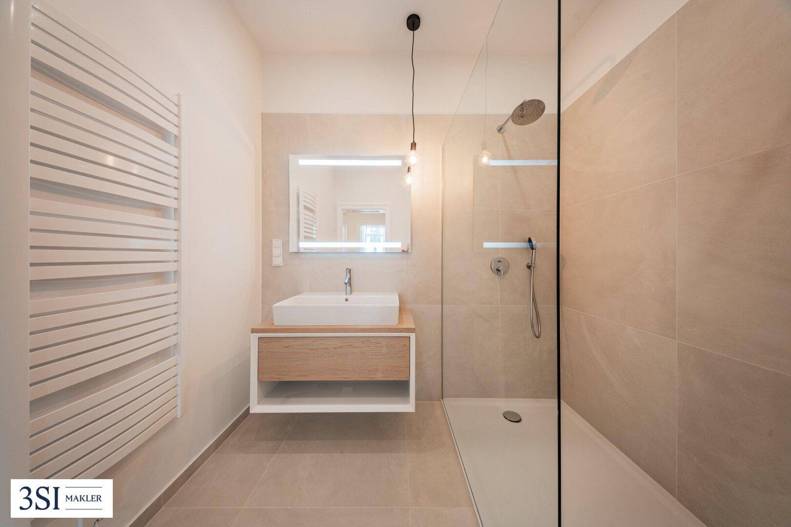 Stilvolles Badezimmer mit großer begehbarer Dusche, modernem Waschtisch und integriertem Spiegel.