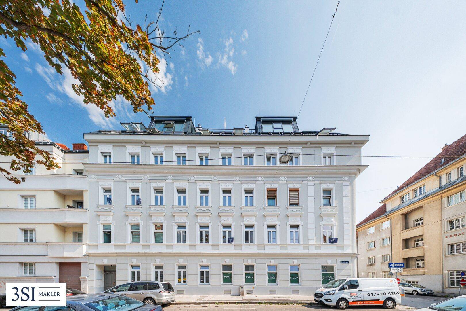 Klassisches Wohngebäude mit vielen Fenstern und einem Mansarddach in städtischer Umgebung.