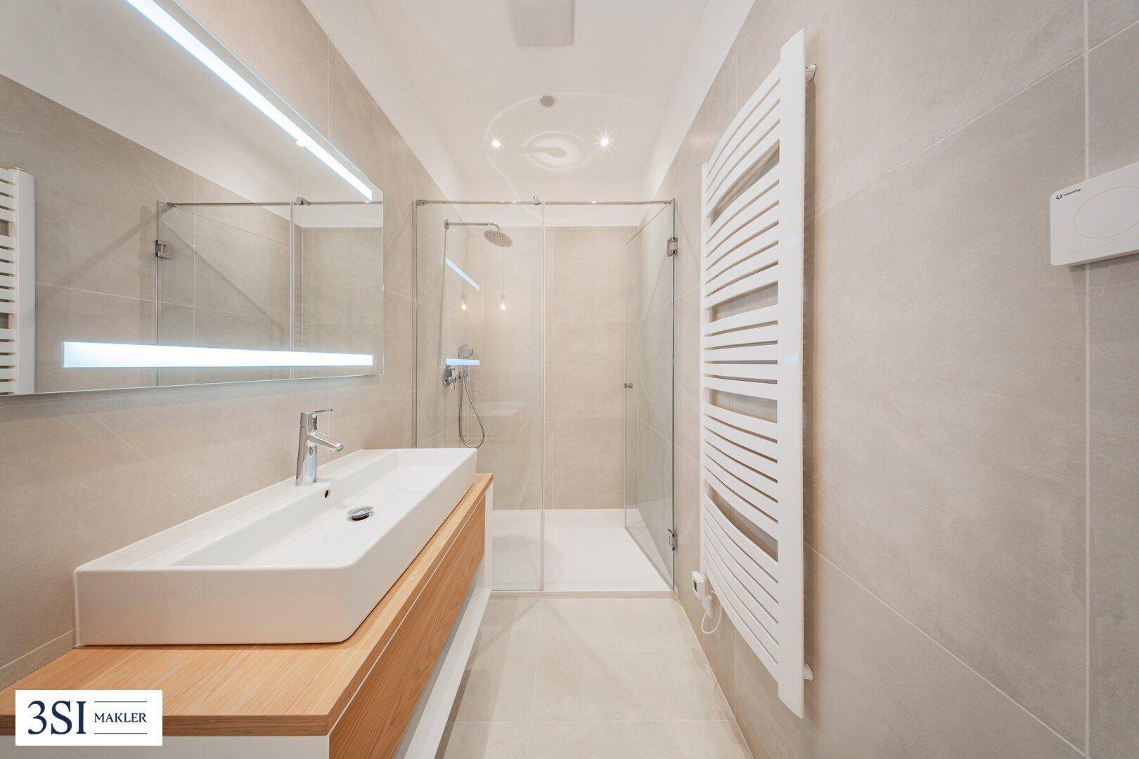 Modernes Badezimmer mit großer begehbarer Dusche, Einzelwaschbecken und beheiztem Handtuchhalter.