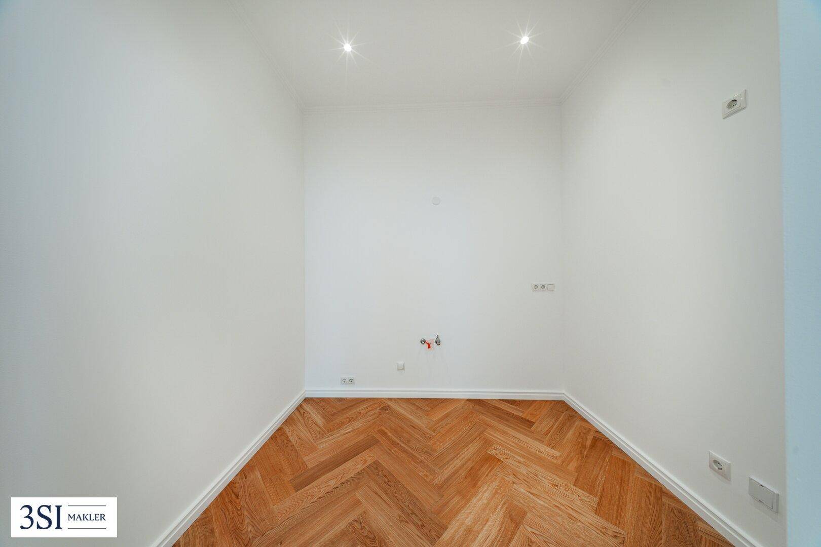 Leerer Küchenraum mit Anschlüssen für Spüle und Geräte, bereit für eine individuelle Gestaltung.