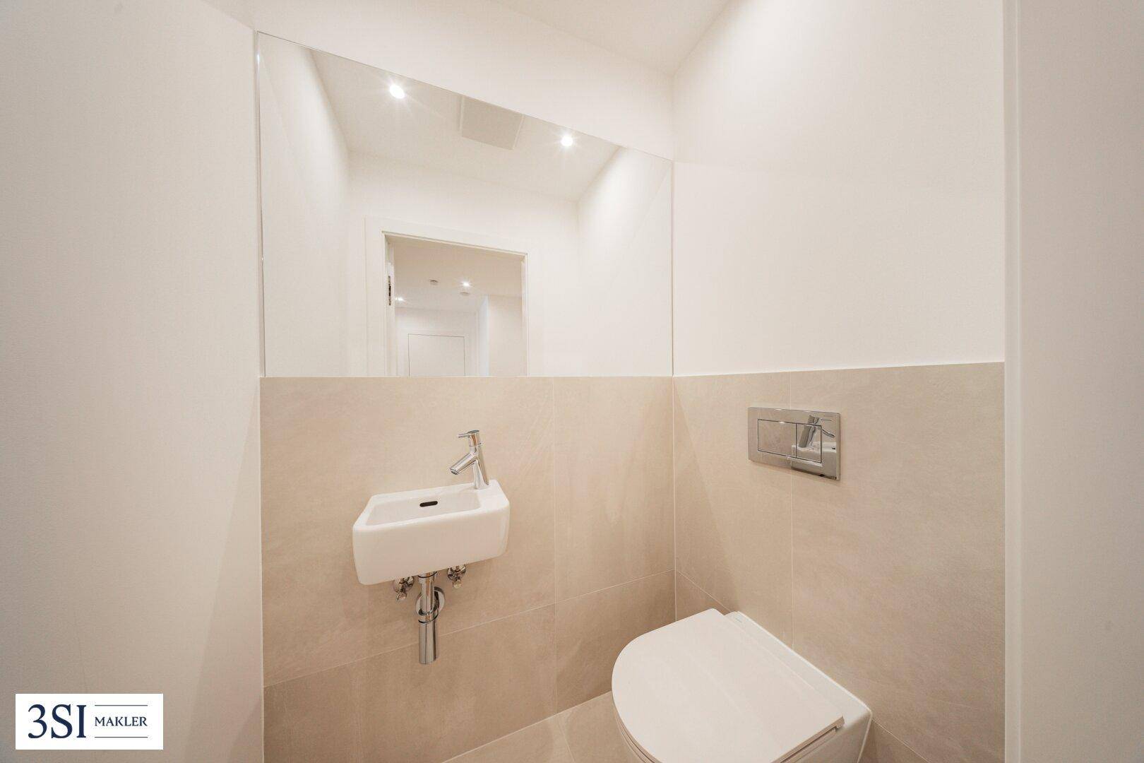Modernes Gäste-WC mit wandhängender Toilette, kleinem Waschbecken und großem Spiegel.