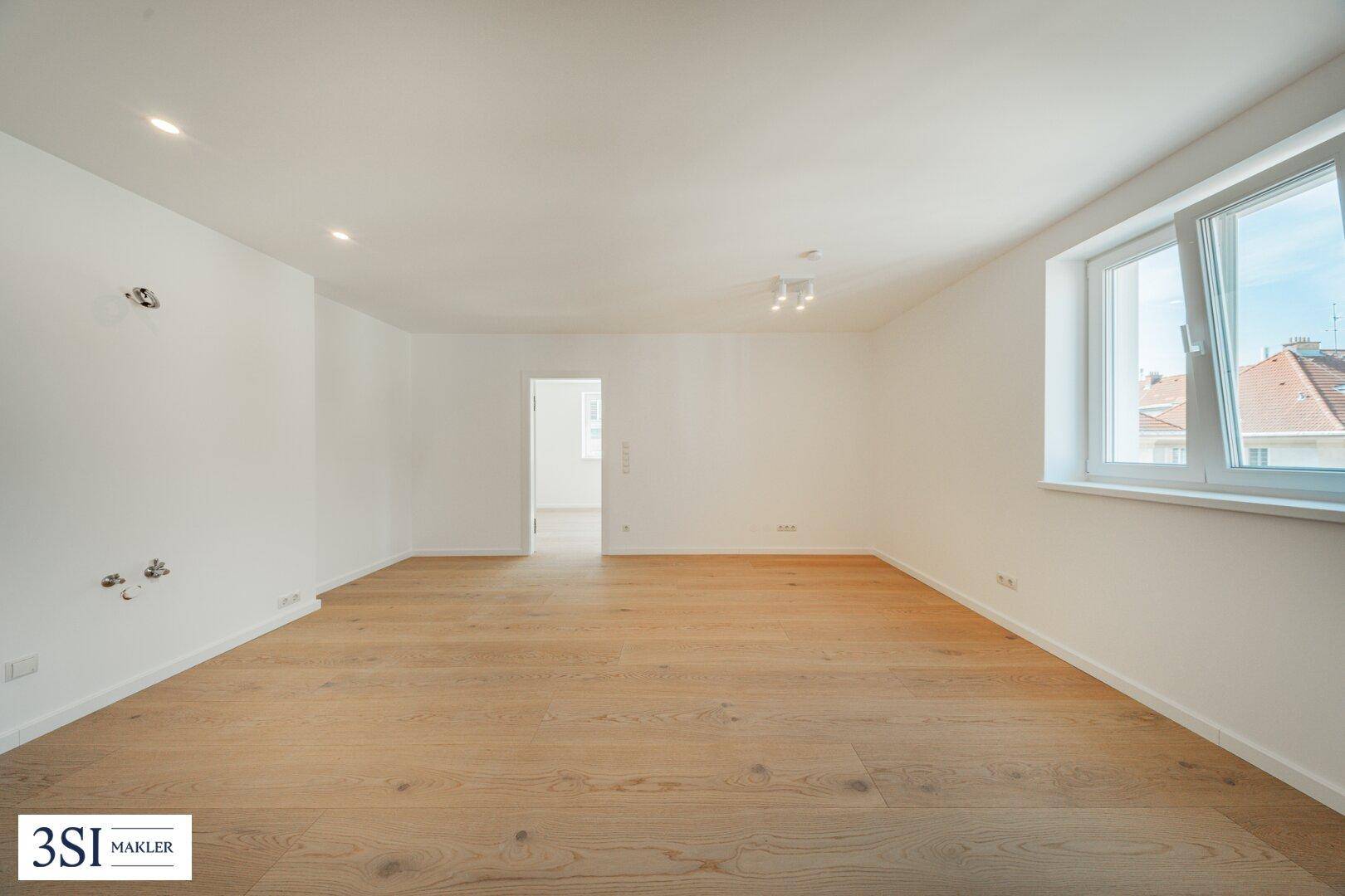 Geräumiger, heller Wohnraum mit Parkettboden und großen Fenstern, bietet viel natürliches Licht.