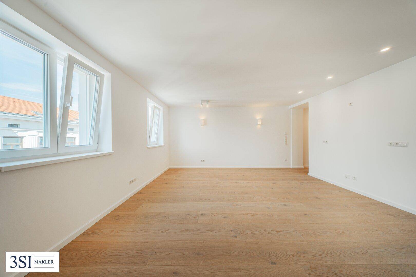 Geräumiger, heller Raum mit Parkettboden und geöffnetem Fenster, bietet viel Tageslicht.