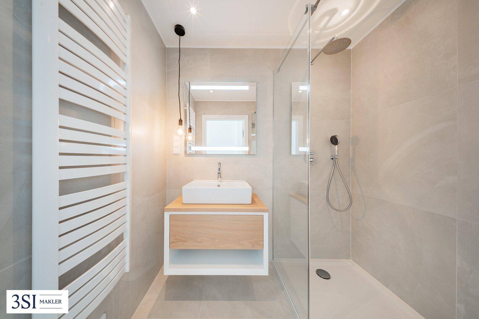 Modernes Badezimmer mit begehbarer Dusche, Einzelwaschbecken und beheiztem Handtuchhalter.