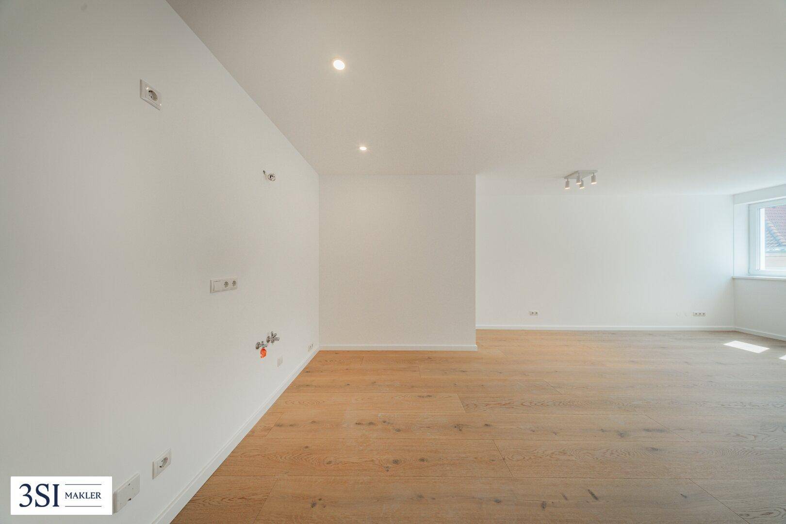 Heller Raum mit Holzboden und weißen Wänden, vorbereitet für Installationen.