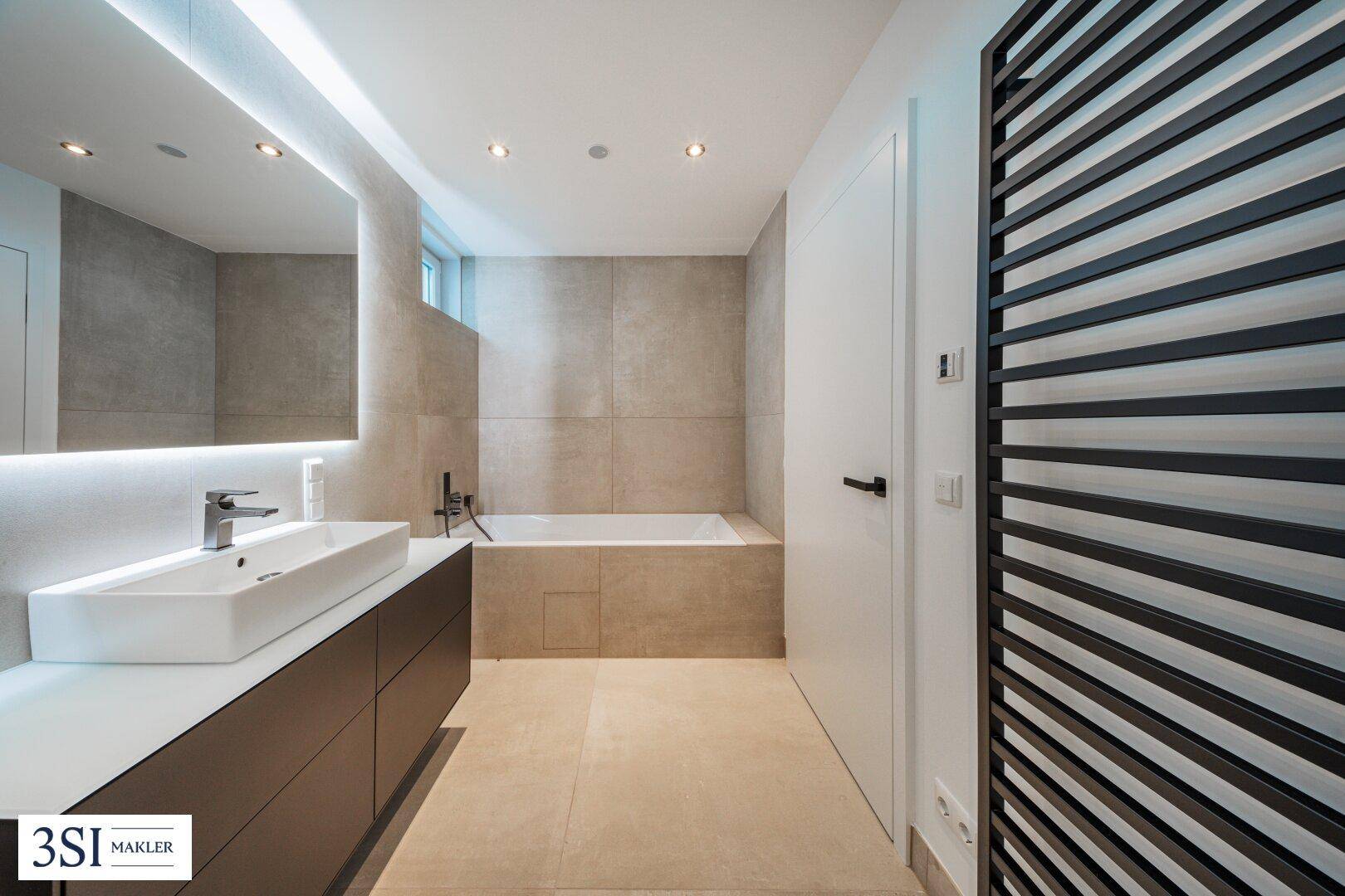 Modernes Badezimmer mit Badewanne, Einzelwaschbecken und großem Spiegel.