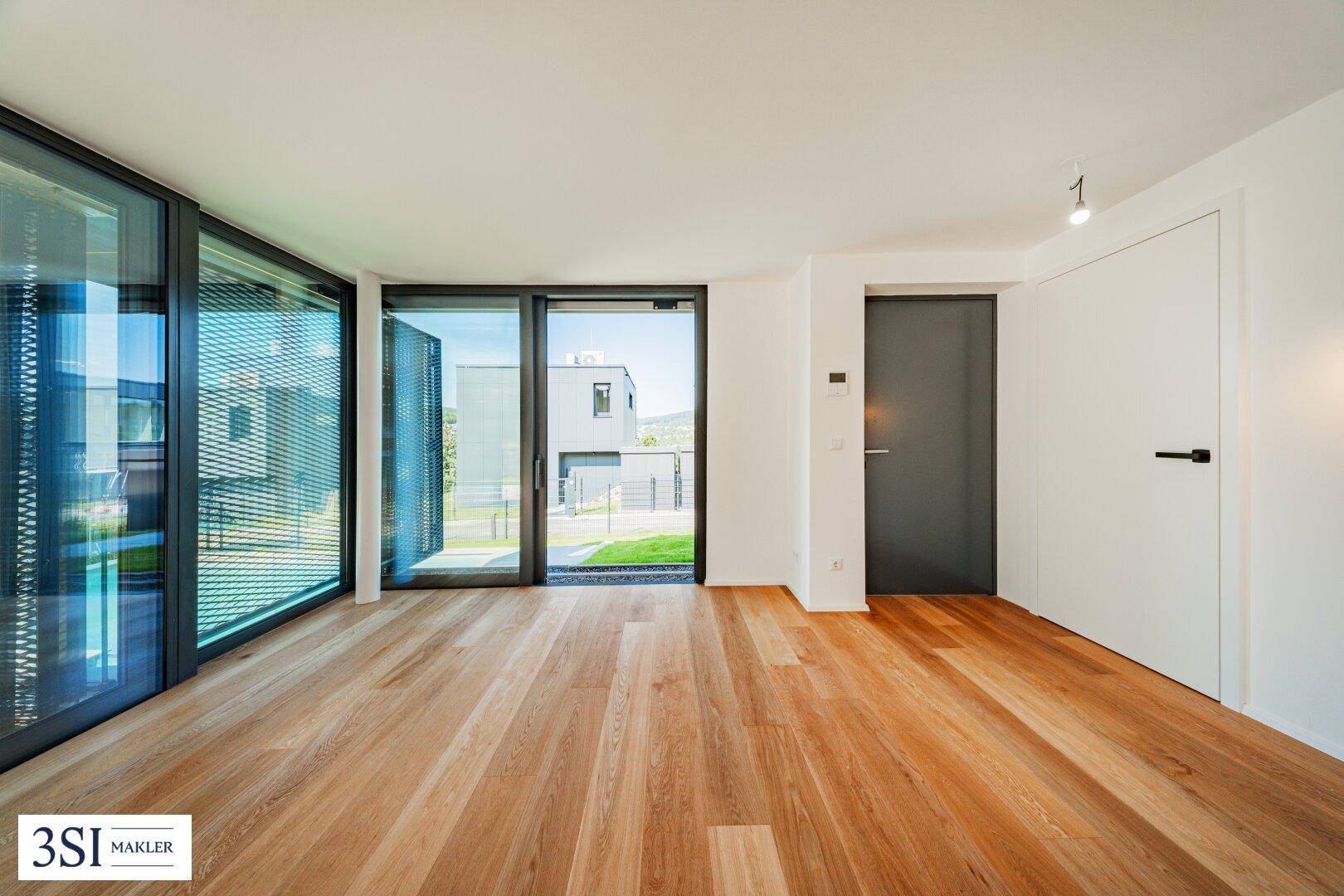 Heller Eingangsbereich oder Wohnraum mit Holzboden und großen Fenstern zur Umgebung.