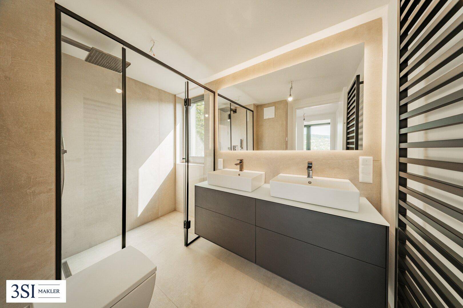 Geräumiges Badezimmer mit Doppelwaschbecken, großer Dusche und beheiztem Handtuchhalter.