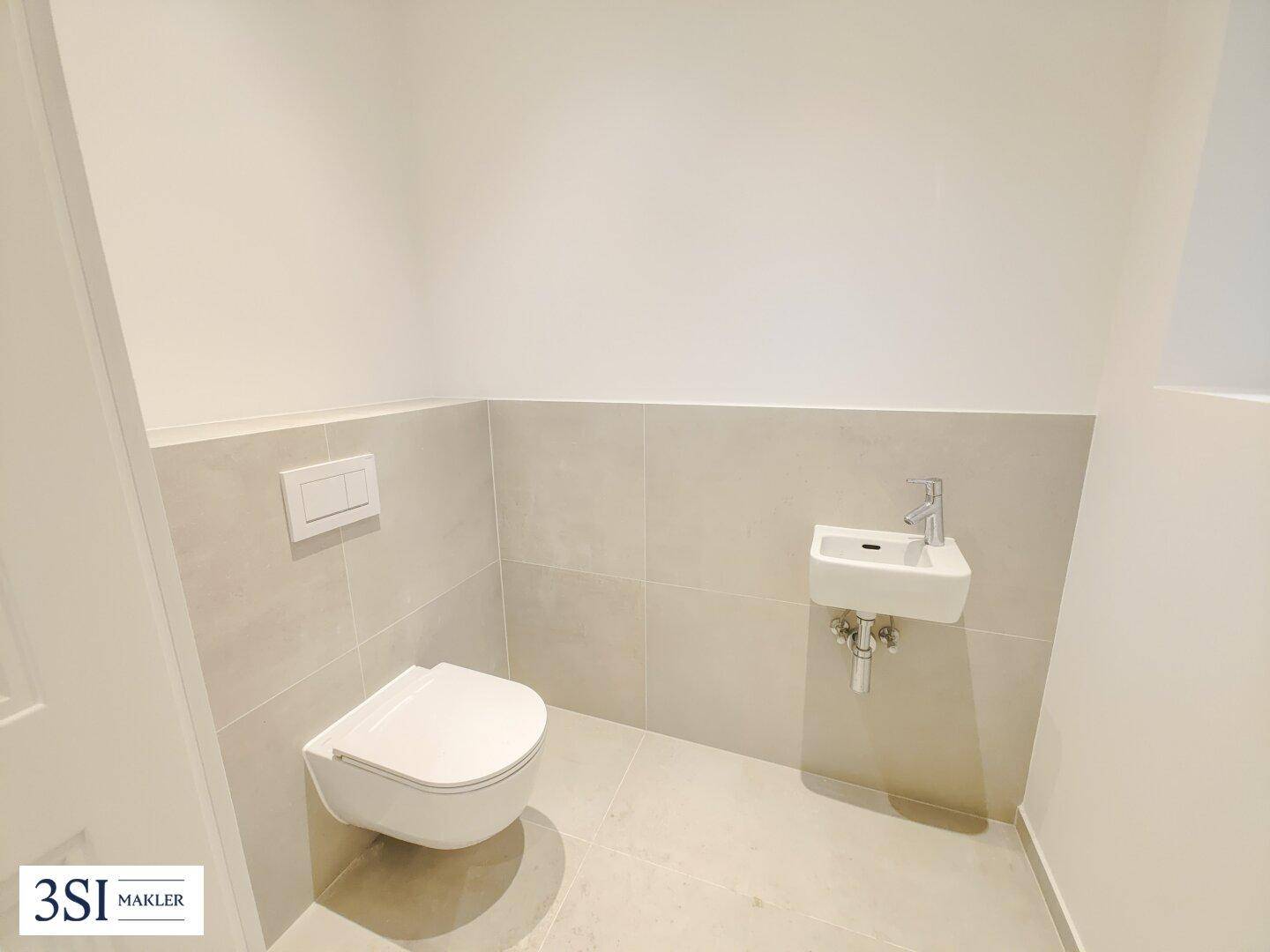 Modernes Gäste-WC mit wandhängender Toilette und kleinem Handwaschbecken.