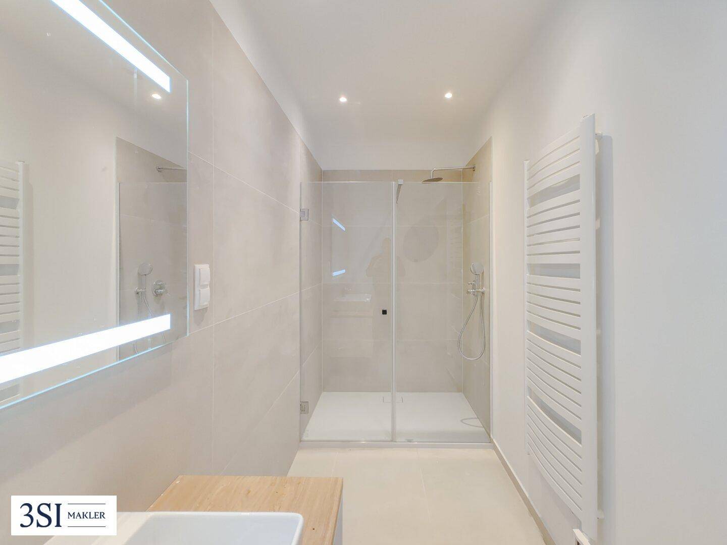 Elegantes Badezimmer mit großer begehbarer Dusche und modernem Handtuchheizkörper.