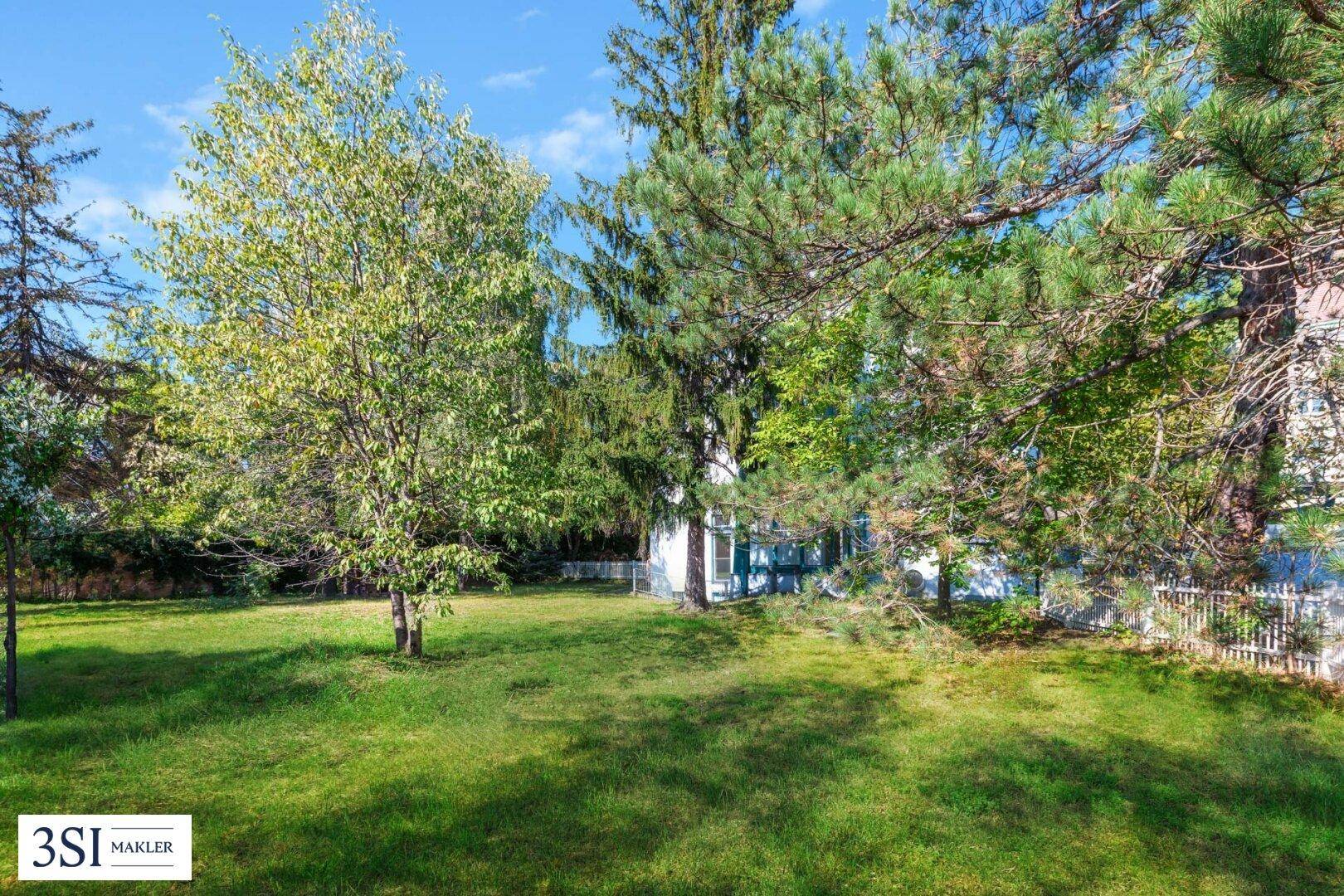 Weitläufiger Gartenbereich mit altem Baumbestand und viel Grün, ideal zum Entspannen und Spielen.