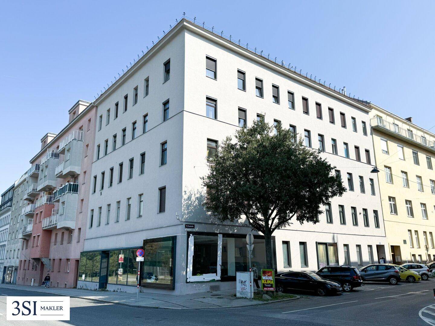 Mehrstöckiges Wohn- und Geschäftsgebäude mit moderner Architektur und großen Fenstern.