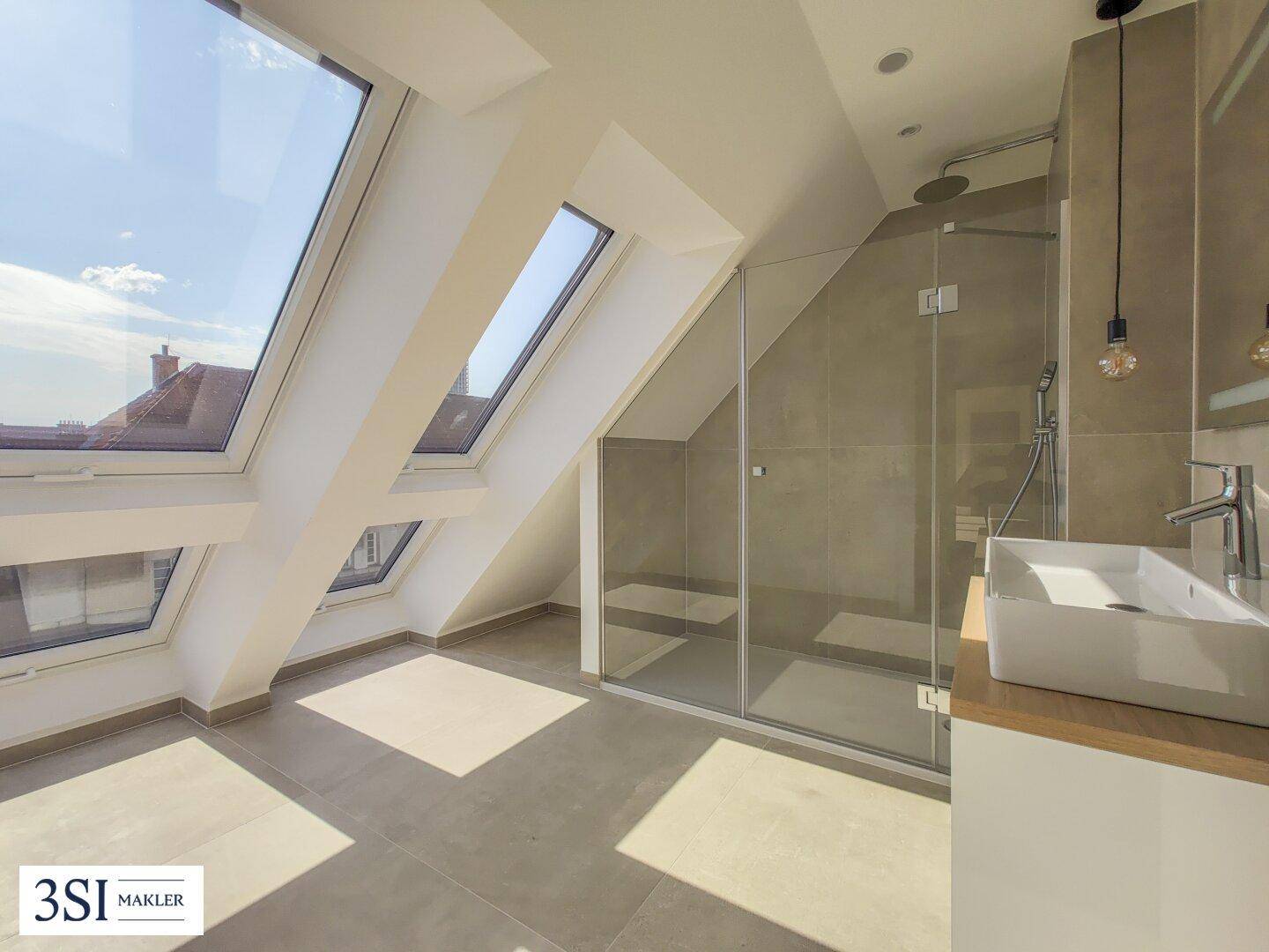 Modernes Badezimmer im Dachgeschoss mit Schrägfenstern, begehbarer Dusche und elegantem Waschtisch.