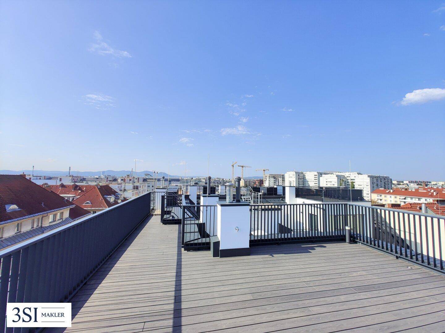 Weitläufige Dachterrasse mit Holzboden und beeindruckendem Blick über die Stadtlandschaft.