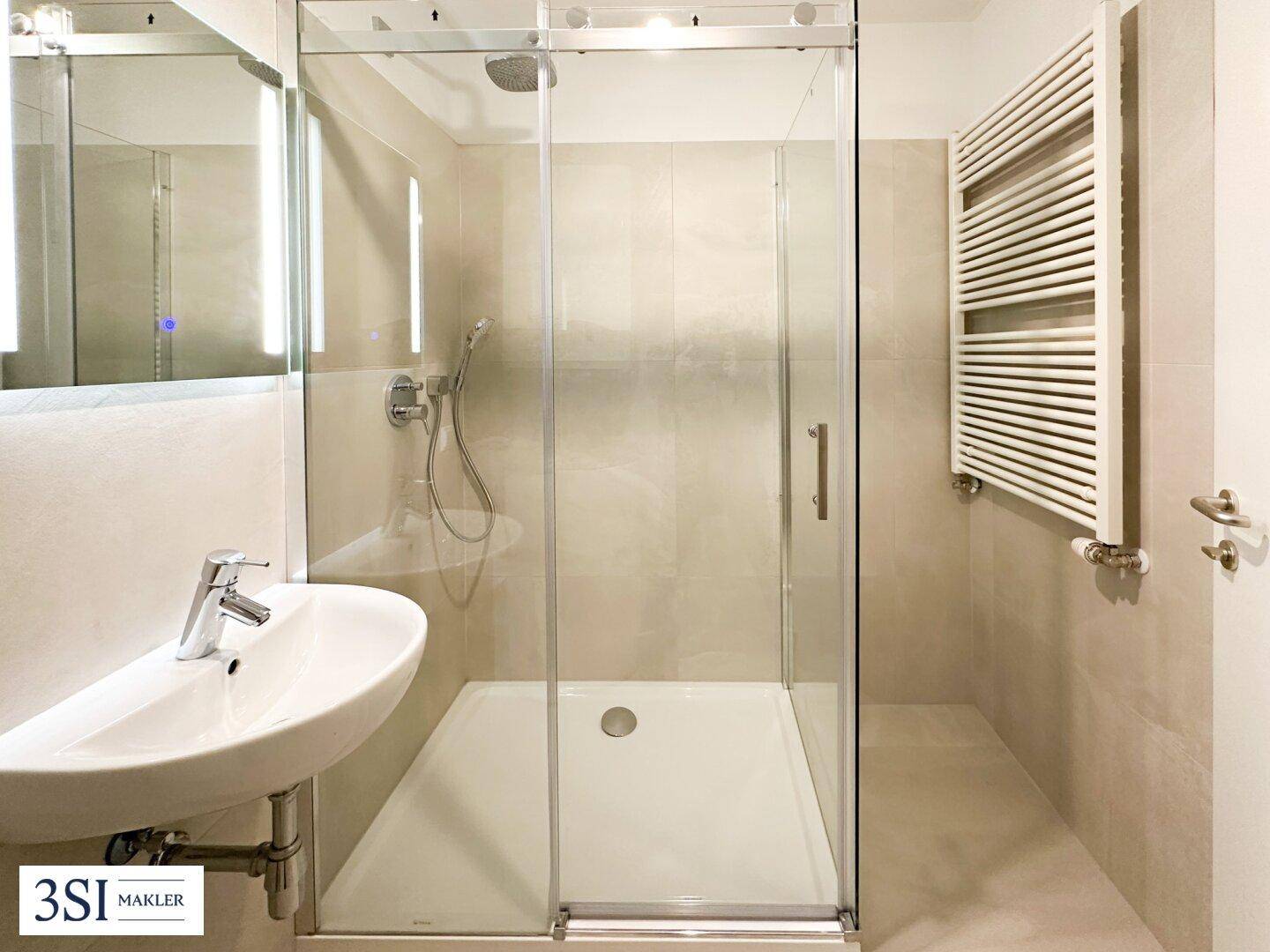 Modernes Badezimmer mit begehbarer Dusche, eleganten Fliesen und beheiztem Handtuchhalter.