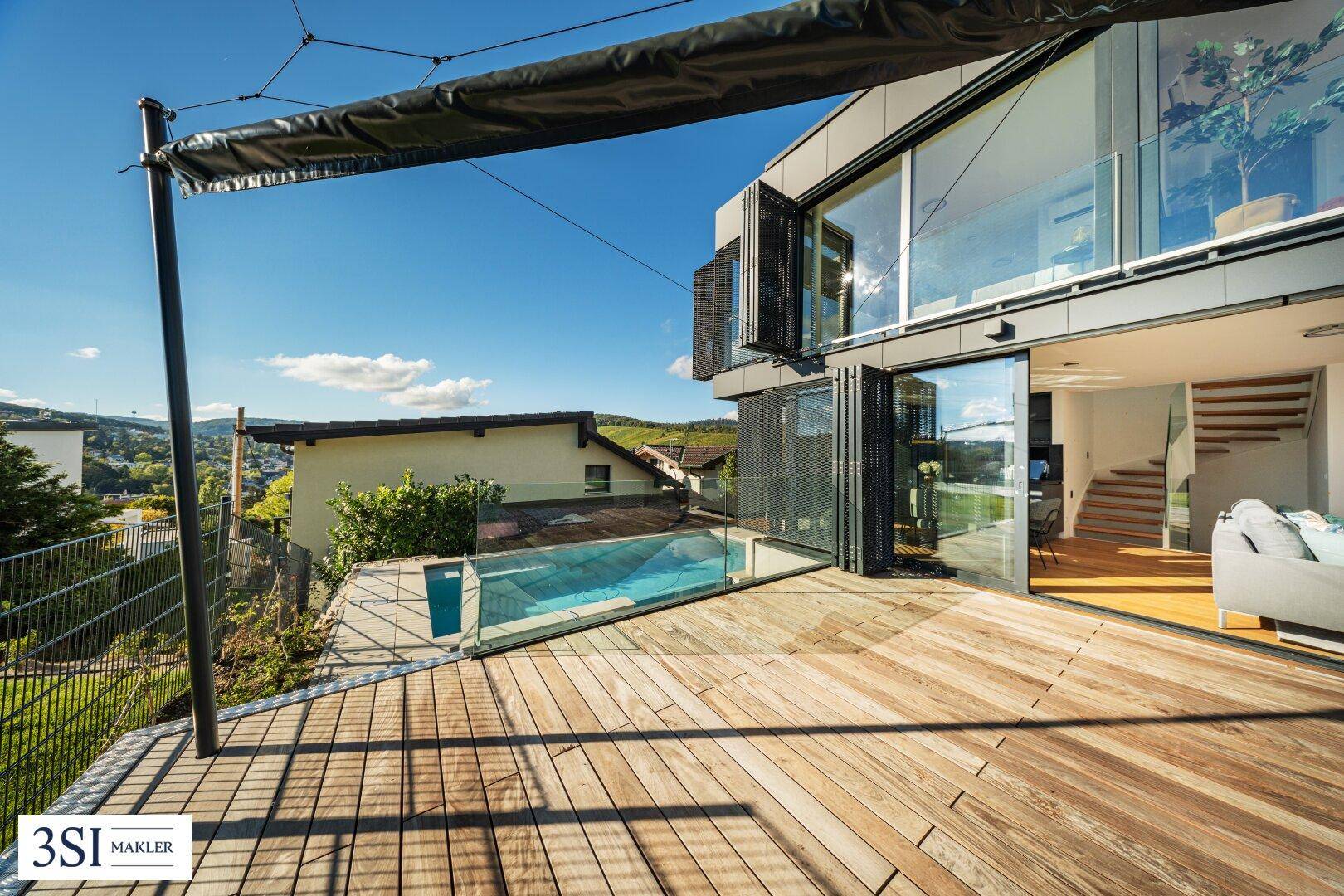 Geräumige Holzterrasse mit Pool und Sonnenschutz, ideal für Entspannung im Freien.