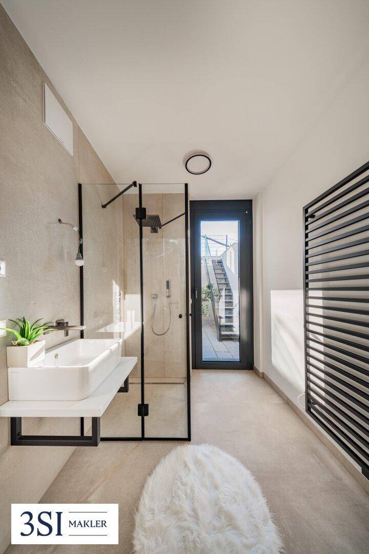 Modernes Badezimmer mit begehbarer Dusche, Einzelwaschbecken und beheiztem Handtuchhalter.