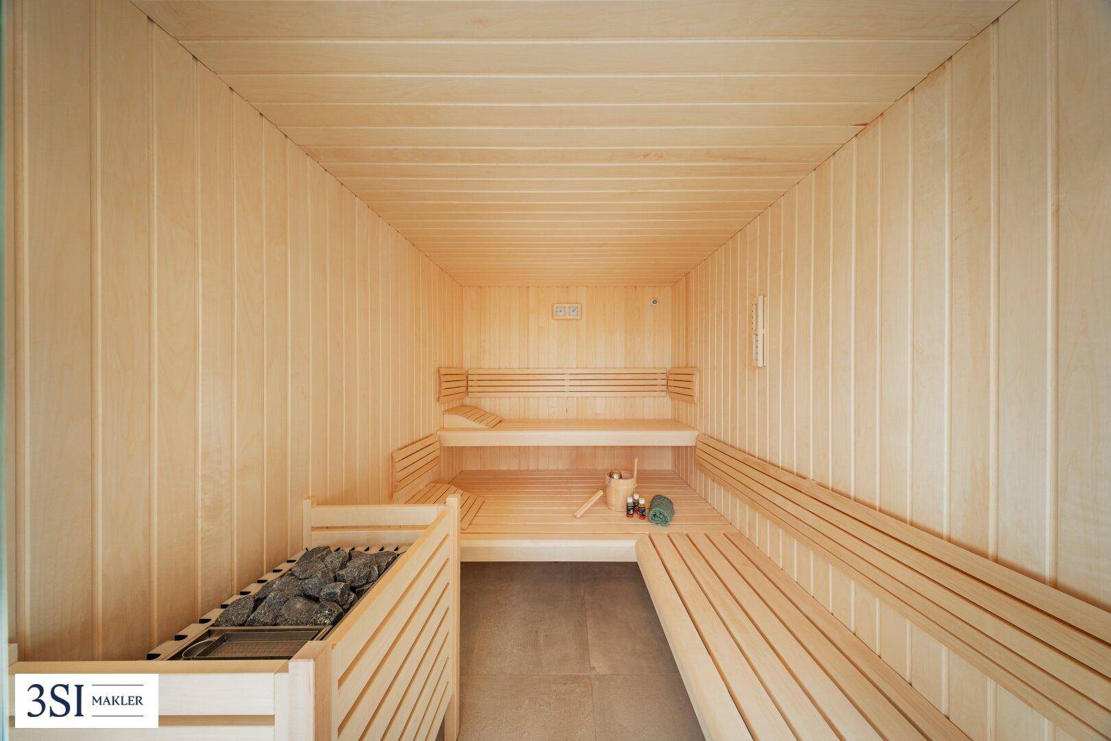 Geräumige Holzsauna mit mehreren Bänken und traditionellem Saunaofen für Wellness.