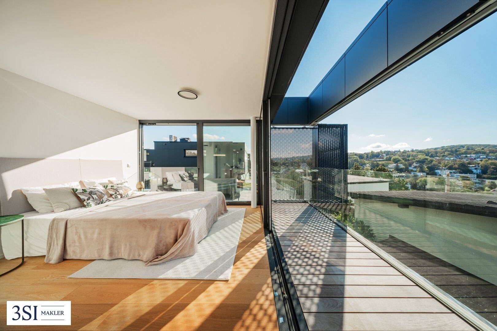 Geräumiges Schlafzimmer mit Holzboden, großen Fensterfronten und Zugang zur Terrasse.
