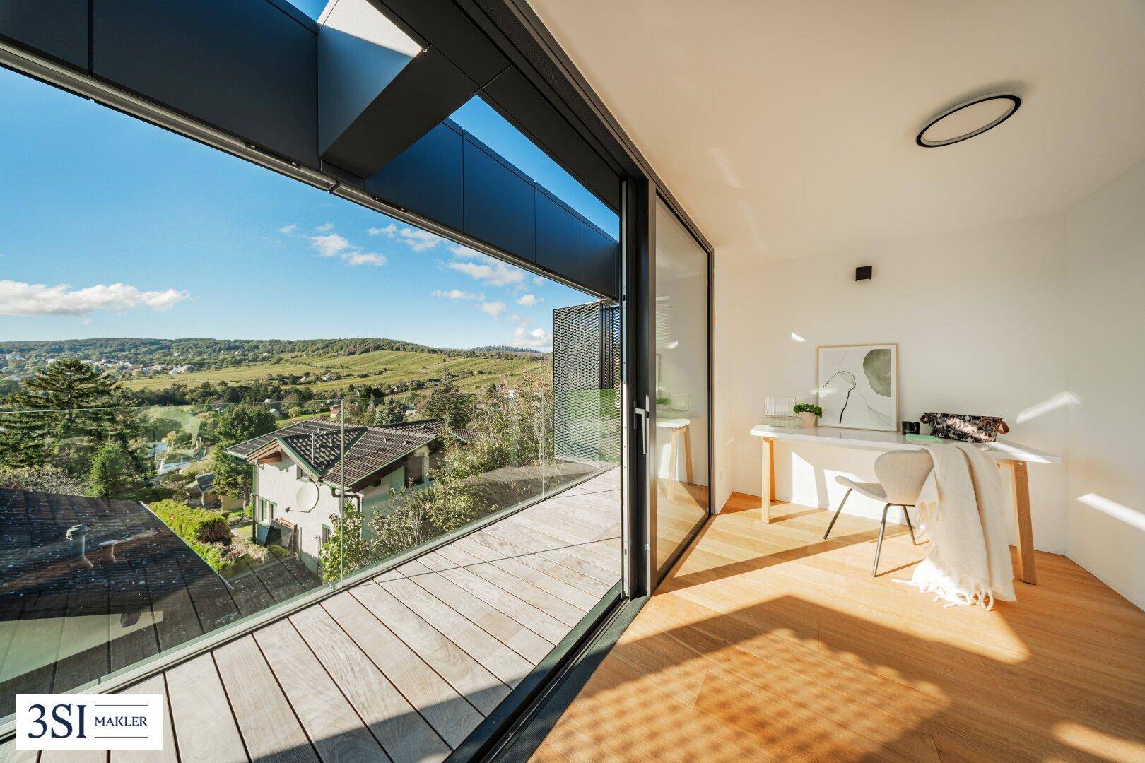 Heller Arbeitsbereich mit Holzboden, großen Fenstern und Panoramablick auf die Umgebung.
