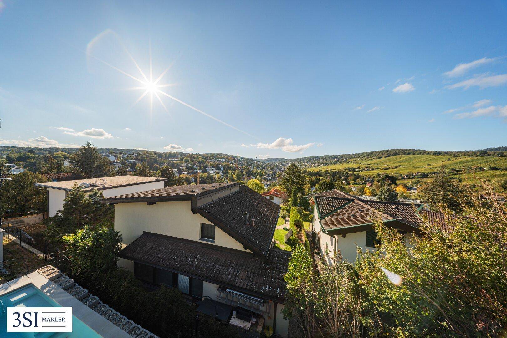 Panoramablick über die hügelige Landschaft mit Wohnsiedlungen und Weinbergen.