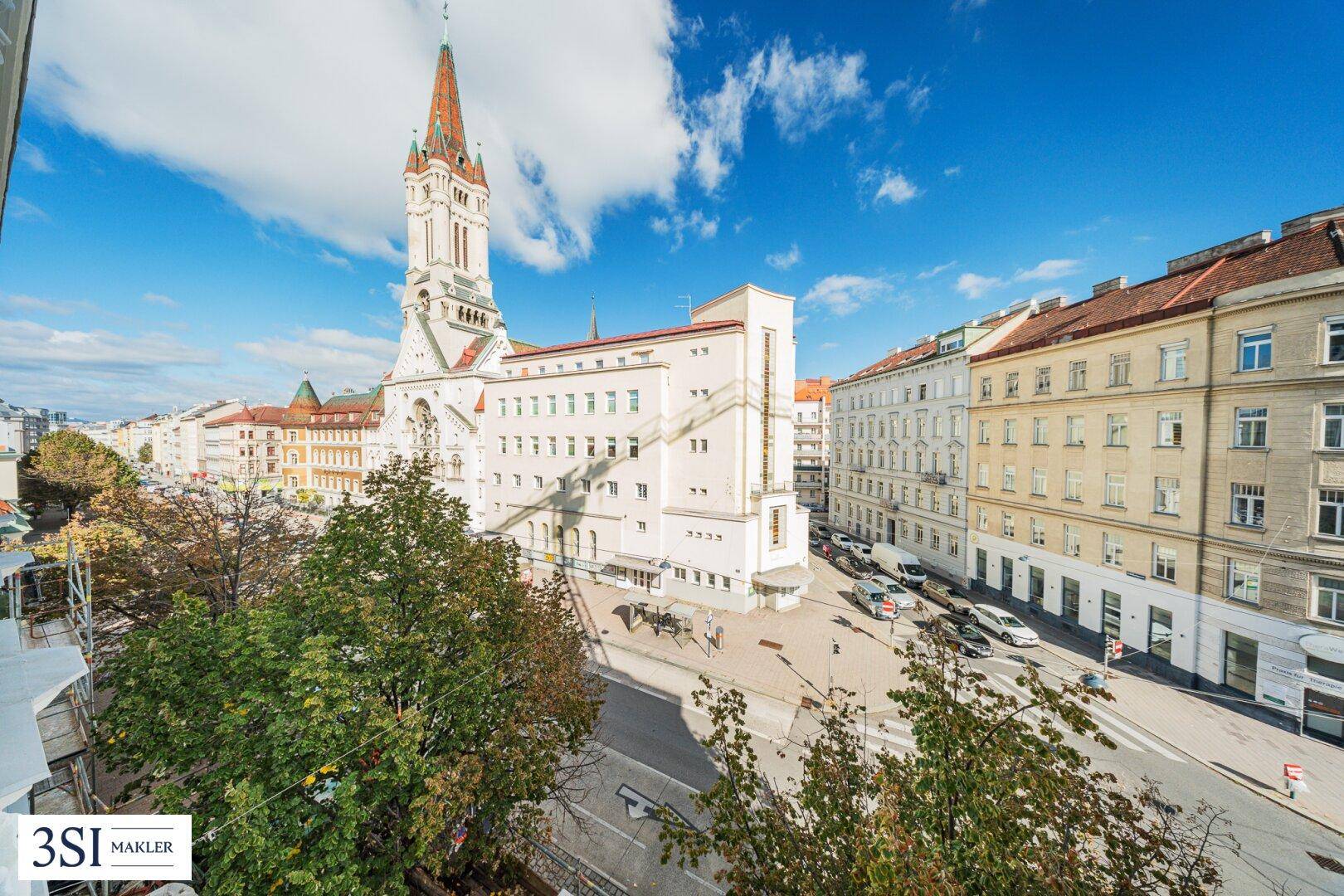 Panoramablick auf eine belebte Stadtstraße mit historischer Kirche und umliegenden Gebäuden.