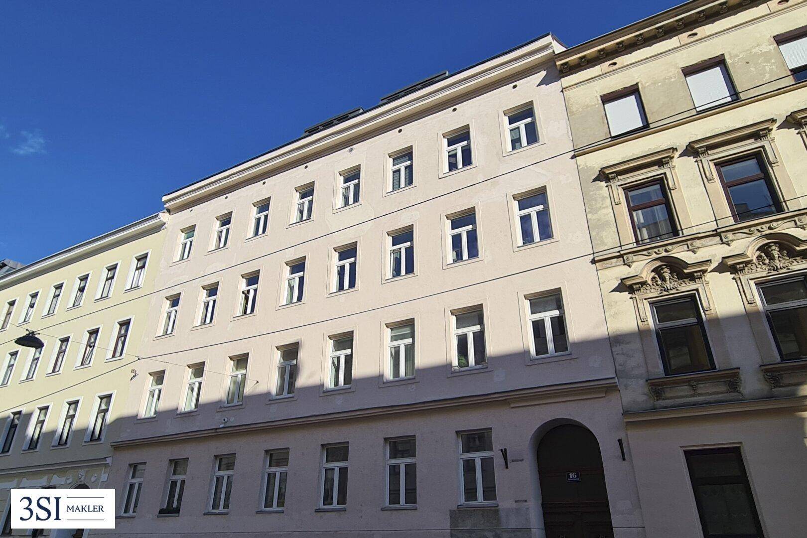 Gesamtansicht der historischen Gebäudefassade mit vielen Fenstern und Eingangsbereich.