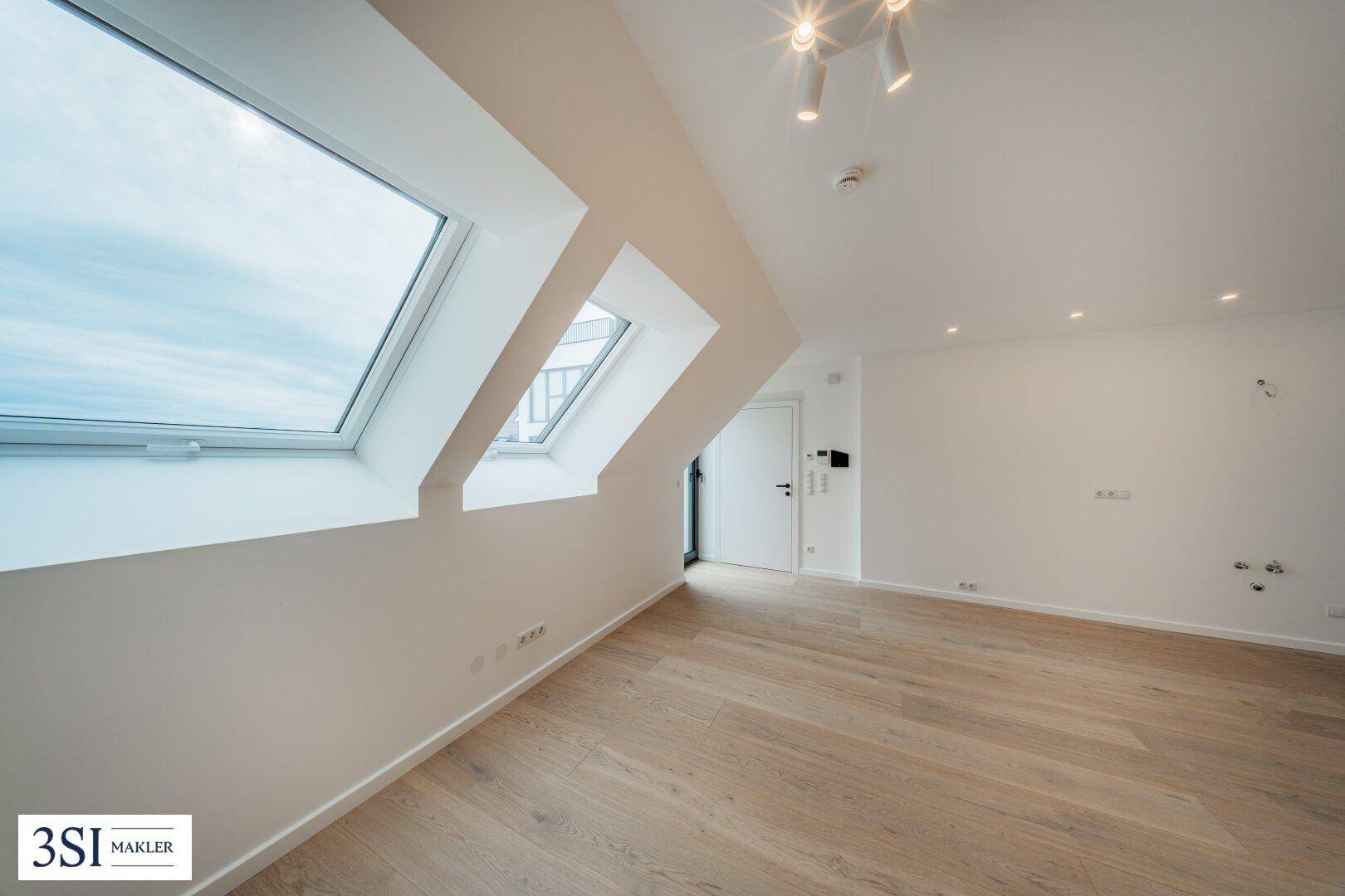 Lichtdurchfluteter Wohnraum im Dachgeschoss mit Holzboden und großen Dachfenstern.