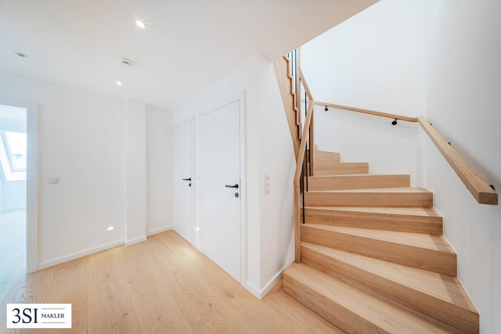 Helle Holztreppe mit modernem Geländer, verbindet die verschiedenen Ebenen der Wohnung.